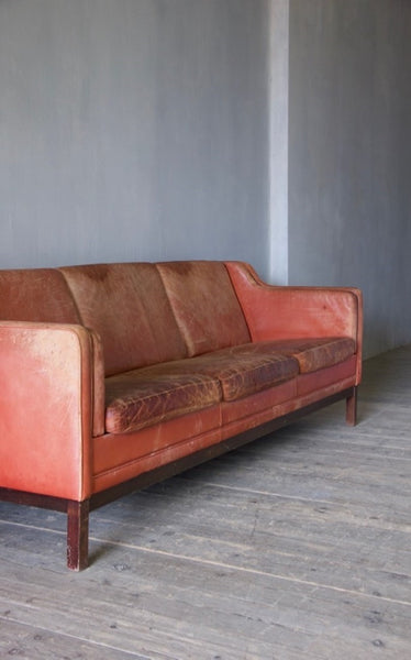 A large mid-century red leather sofa