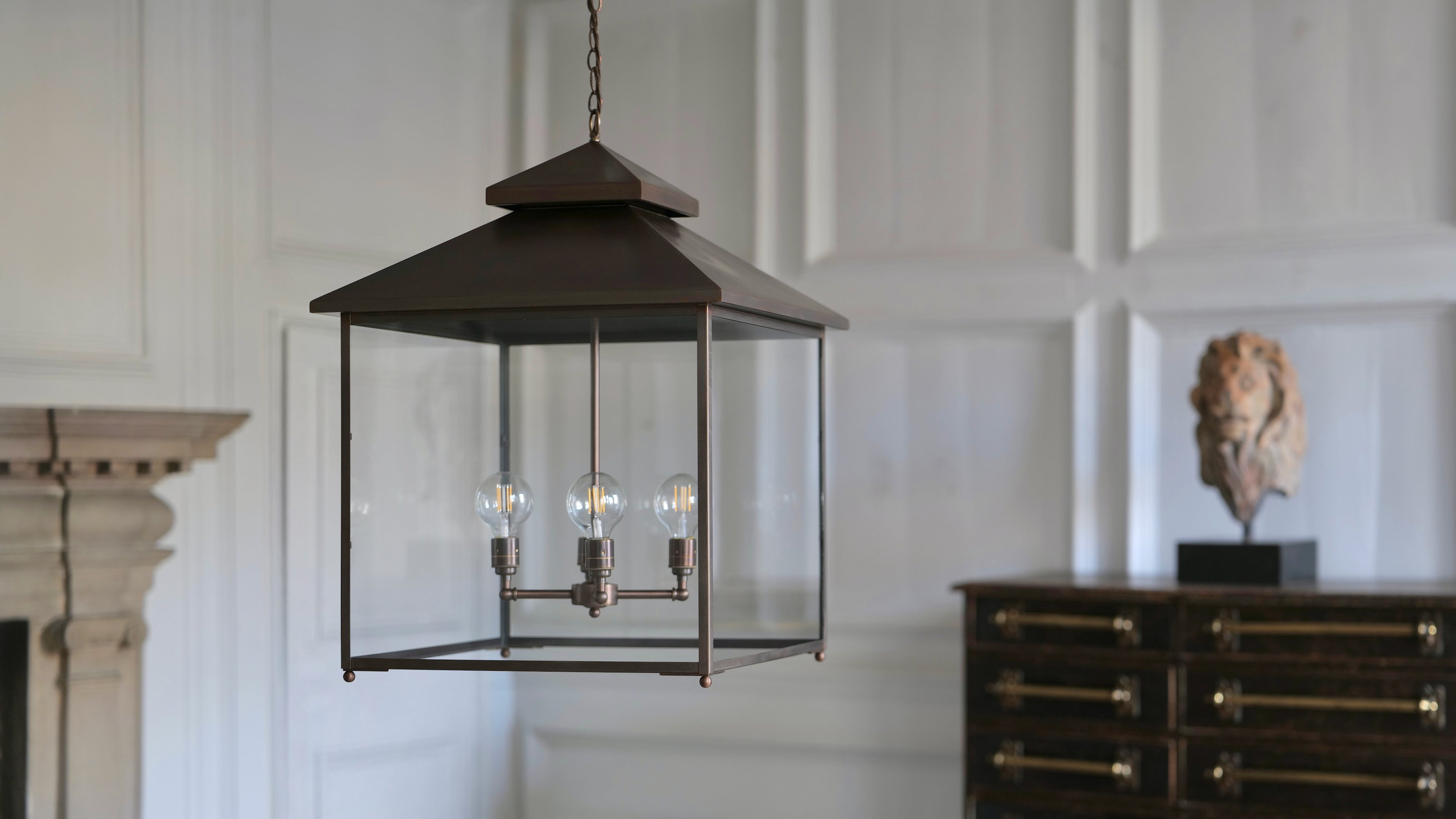 Decorative hanging lantern in a room with a fireplace and sculpture.
