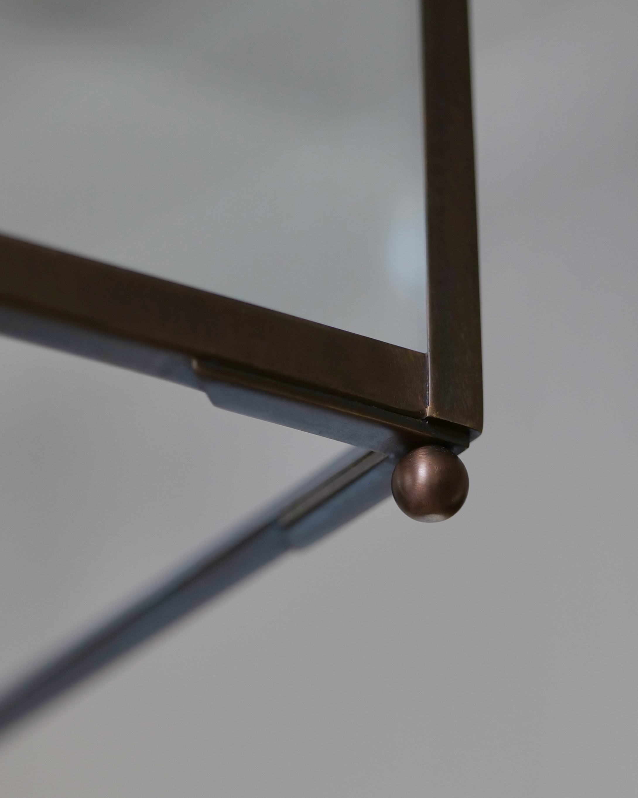 A close-up of the corner detail of a lantern made in a dark-coloured brass and glass.