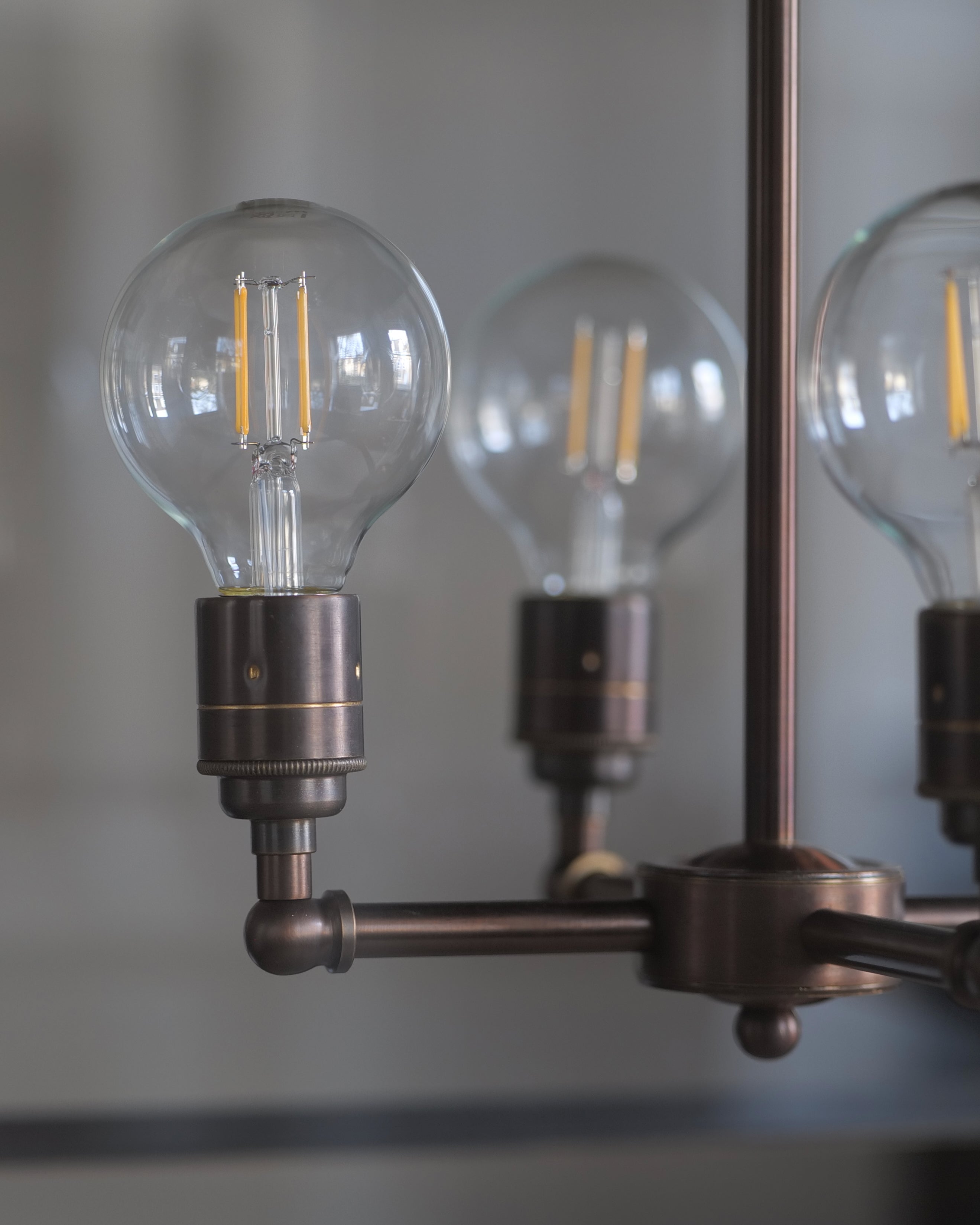 A close-up detail image of the 4-way centre of a lantern made from a dark finished brass and clear glass.