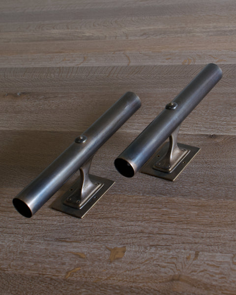 Two cylindrical dark brass lighting fixtures with mounting plates, shown on a rustic wood plank surface.