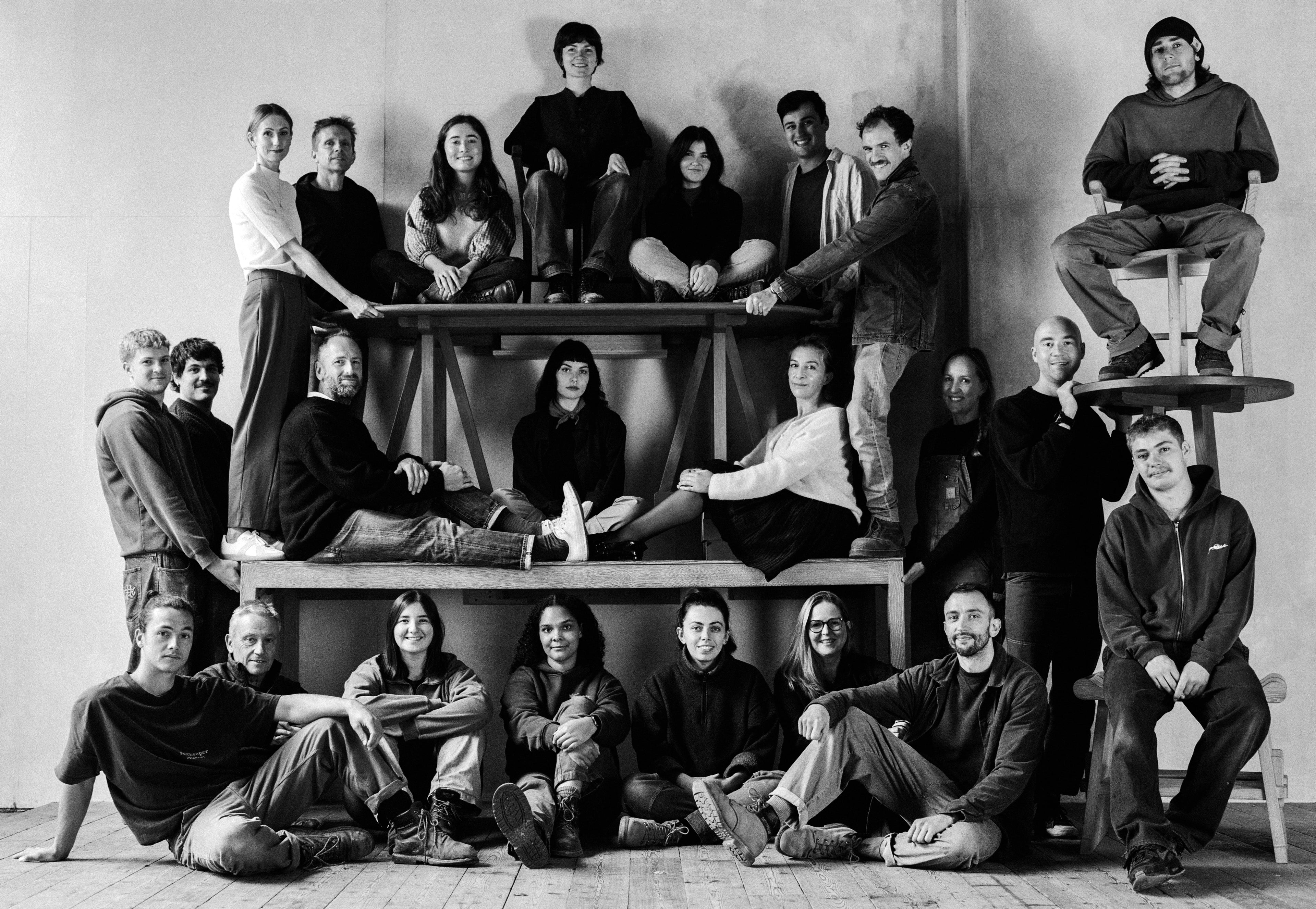 Group of people seated on stacked furniture pattern on a wooden floor.