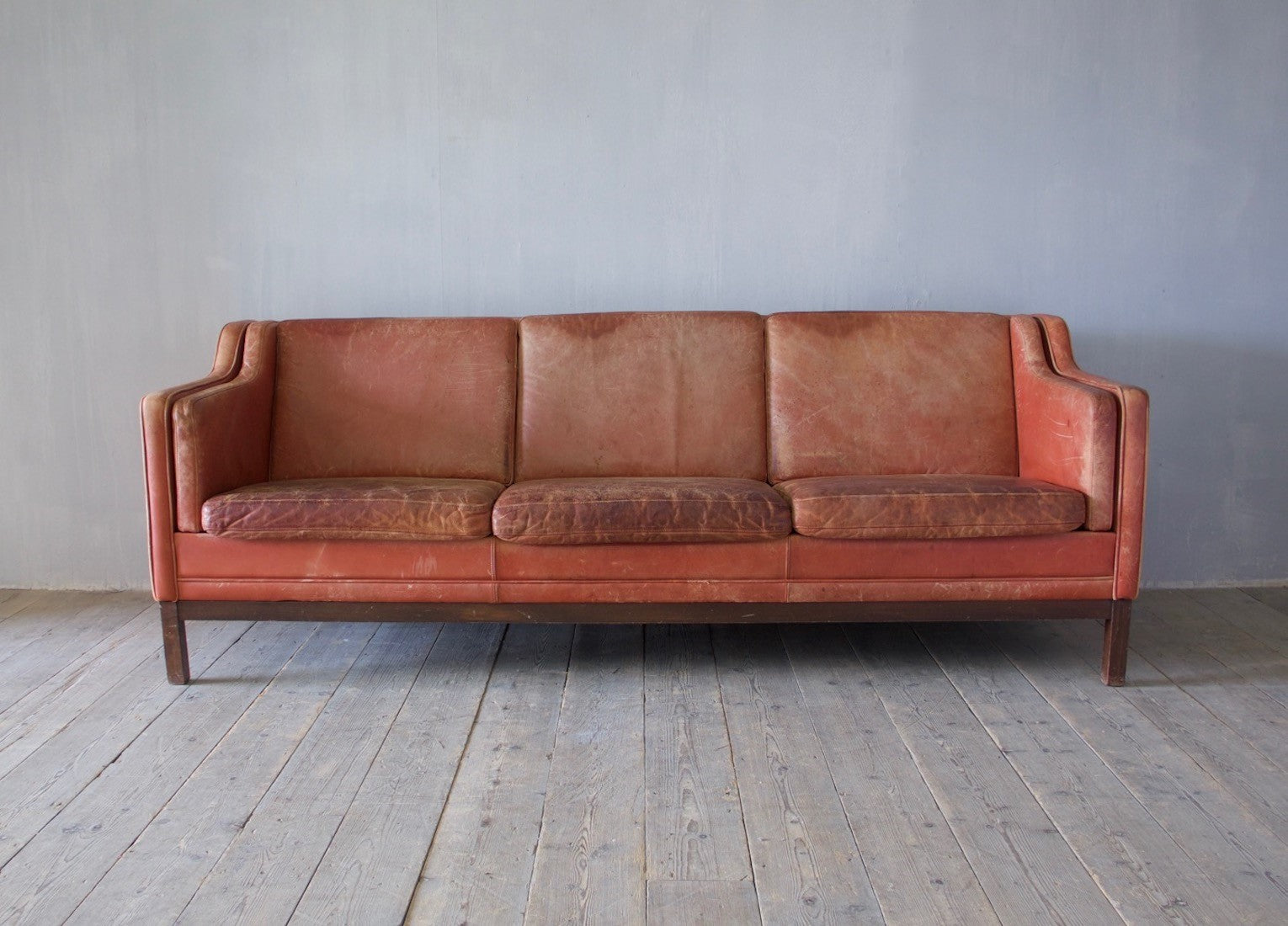 A large mid-century red leather sofa