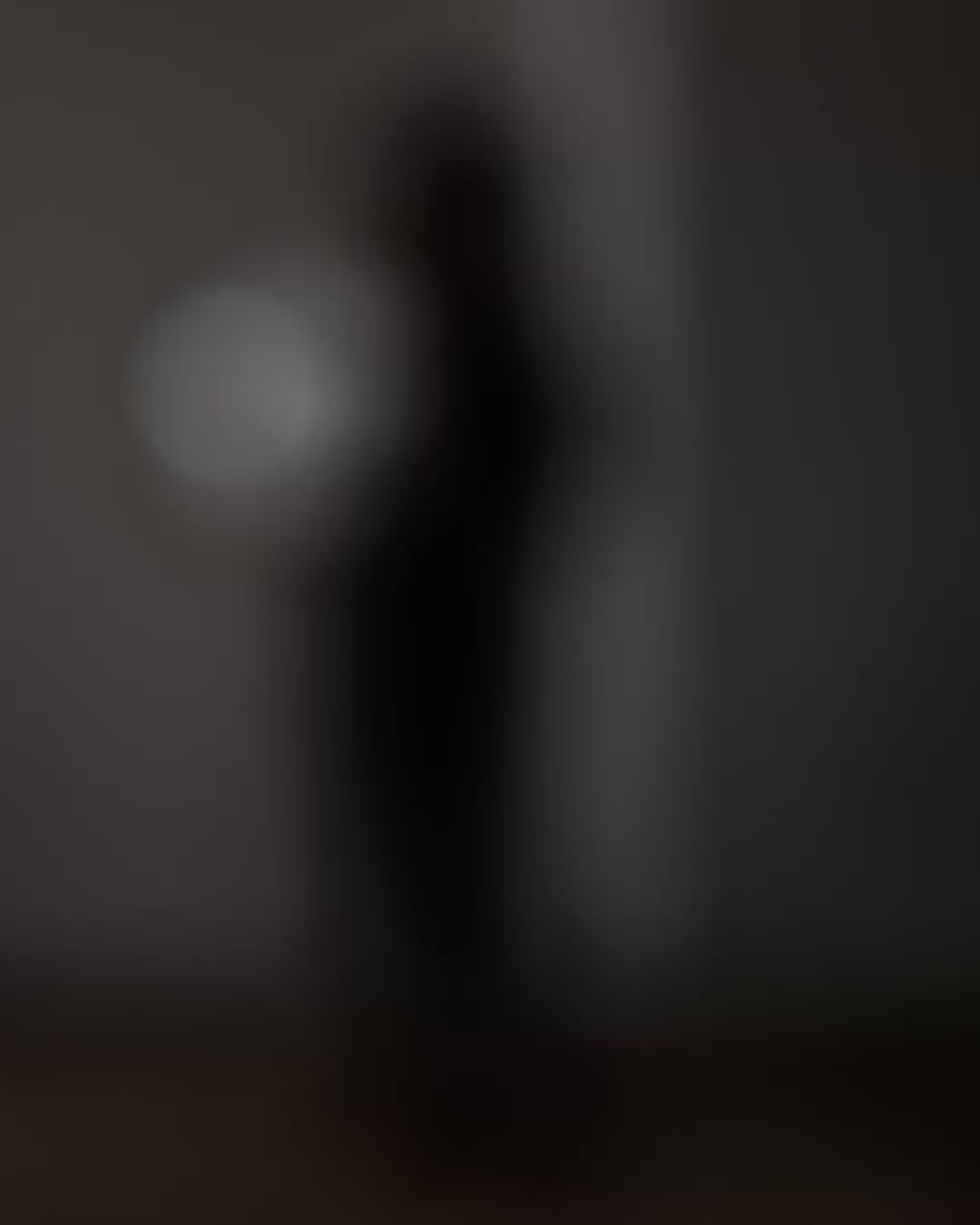 A video showing a female dressed in black, with dark hair, holding a round wall light with a clear glass dome.